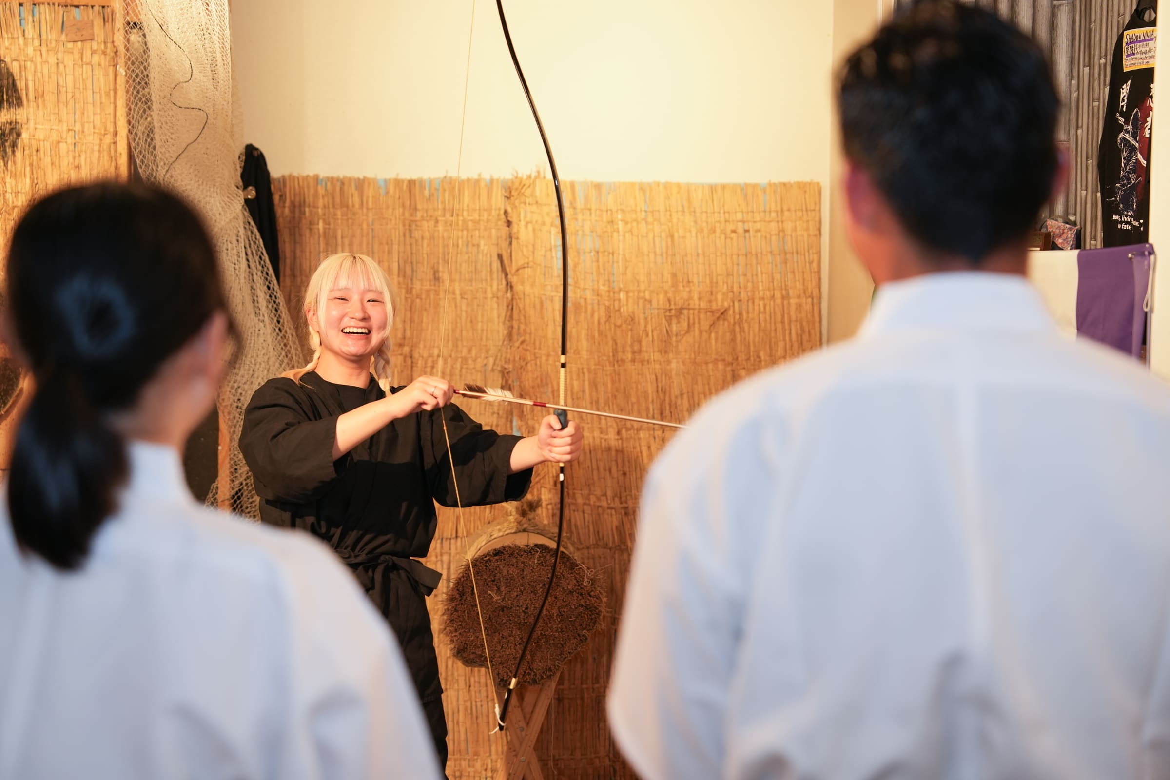 Smiling kyudo instructor teaching basic bow and arrow handling to guests at a Japanese archery experience